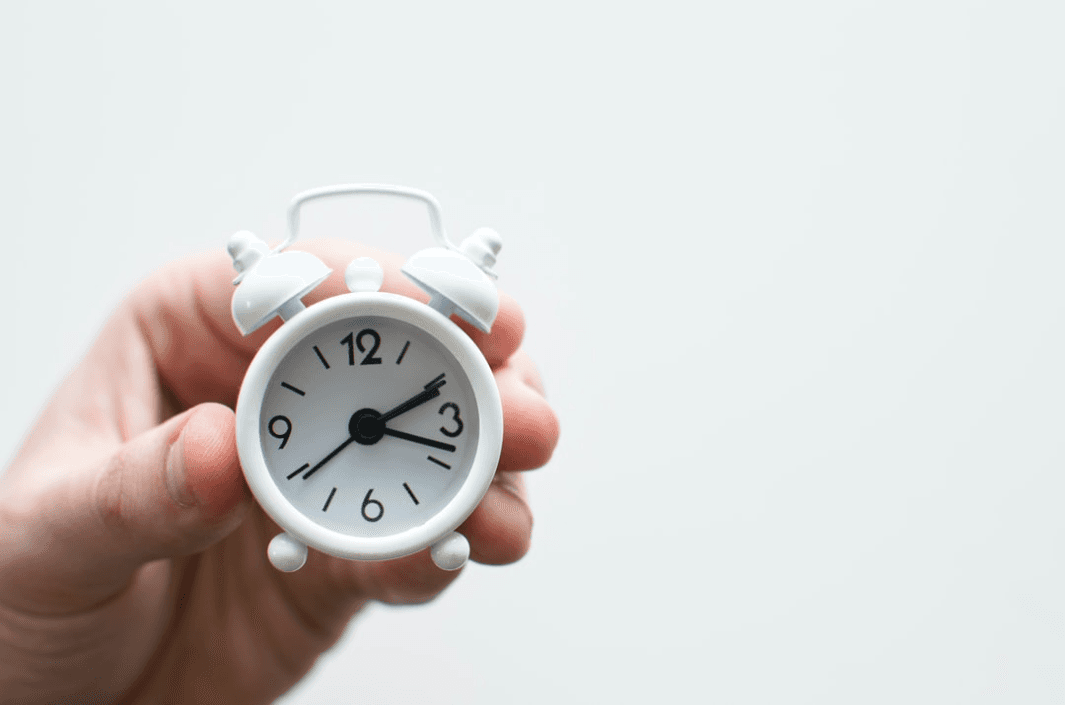 Person Holding White Mini Bell Alarmclock